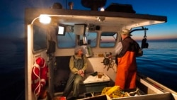 Virginia Oliver, left, chats with her son Max Oliver while heading out to sea to fish for lobster at dawn, Tuesday, Aug. 31, 2021, off Rockland, Maine. (AP Photo/Robert F. Bukaty)