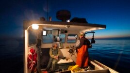 Virginia Oliver, left, chats with her son Max Oliver while heading out to sea to fish for lobster at dawn, Tuesday, Aug. 31, 2021, off Rockland, Maine. (AP Photo/Robert F. Bukaty)