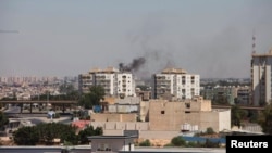Smoke rises near buildings after heavy fighting between rival militias broke out near the airport in Tripoli July 20, 2014.