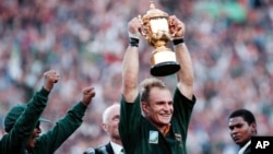 FILE - South African rugby captain Francios Pienaar, center, raises the Rugby World Cup trophy after receiving it from South African President Nelson Mandela, left, at Ellis Park, Johannesburg, South Africa, June 24, 1995.