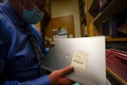 Tom Baumgarten, superintendent of the Morongo Unified School District, looks at a laptop with a cracked screen at Twentynine Palms Junior High School, Aug. 18, 2020, in Twentynine Palms, Calif.