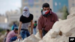 Palestinian demonstrators take cover during clashes with Israeli troops near Ramallah, West Bank, Sept. 29, 2015. 