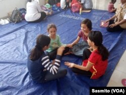 Pekerja sosial Dinas Sosial DKI Jakarta, bermain bersama anak-anak di lobby bangunan bekas Kodim 0504 di Jakarta Barat, Rabu, 17 Juli 2019. (Foto: VOA/Sasmito)