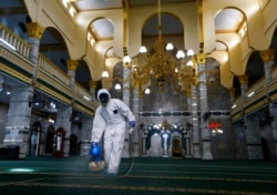 Seorang petugas medis mengenakan pakaian hazmat menyemprotkan disinfektan di sebuah masjid di tengah wabah virus corona, di Jakarta, 13 Maret 2020. (Foto: Reuters)