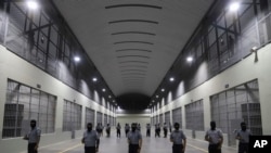 Guardias civiles de la Dirección General de Prisiones se colocan afuera de las celdas en el Centro de Confinamiento del Terrorismo durante una gira de medios en Tecoluca, El Salvador, el jueves 2 de febrero de 2023. 