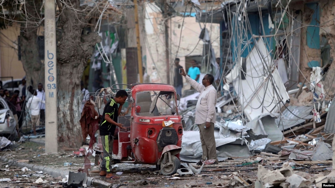 People stand on the rubble of buildings damaged when a suicide car bomb exploded, targeting a Mogadishu hotel in a business center in Maka al-Mukaram street, Mogadishu, Somalia, March 1, 2019. 