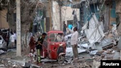 People stand on the rubble of buildings damaged when a suicide car bomb exploded, targeting a Mogadishu hotel in a business center in Maka al-Mukaram street, Mogadishu, Somalia, March 1, 2019. 