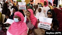 Seorang perempuan memegang poster yang bertuliskan "LGBT adalah ancaman bagi kemanusiaan" dalam sebuah aksi protes menentang homoseksualitas yang dilakukan oleh kelompok agama di alun-alun Obelisque di Dakar, Senegal, pada 23 Mei, 2021. (Foto: AFP/Seyllou)