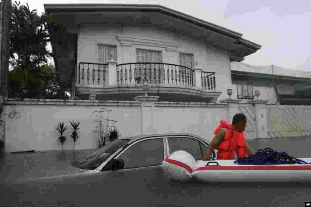 A private guard searches homes to rescue residents trapped in a flooded street at a subdivision in Makati city, east of Manila, August 20, 2013.