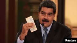 Presiden Venezuela Nicolas Maduro memegang uang kertas baru "Bolivar Soberano" di Caracas. 