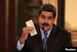 Venezuela's President Nicolas Maduro holds a bank note from the new Venezuelan currency Bolivar Soberano (Sovereign Bolivar), as he speaks during a meeting with ministers at Miraflores Palace in Caracas, Aug. 17, 2018.
