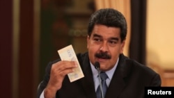 Le président vénézuélien Nicolas Maduro tient un billet de banque de la nouvelle monnaie vénézuélienne Bolivar Soberano (Souverain Bolivar), lors d'une réunion avec les ministres au palais Miraflores à Caracas, Venezuela, le 17 août 2018. 
