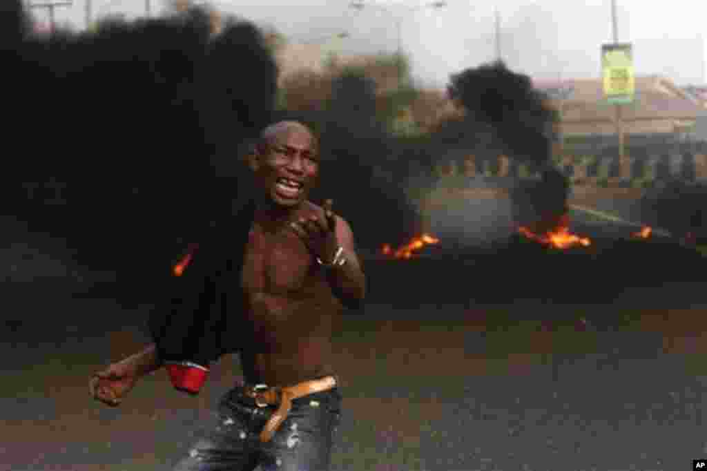 A angry youth protest in front of a burning barrier following the removal of a fuel subsidy by the government in Lagos, Nigeria, Tuesday, Jan. 10, 201. Angry youths erected a burning roadblock outside luxury enclaves in Nigeria's commercial capital Tuesda