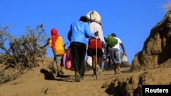 Ethiopians, who fled fighting in Tigray region, carry their belongings after crossing the Setit River on the Sudan-Ethiopia border, in eastern Kassala state, Sudan, Dec. 16, 2020.