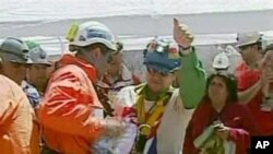 Esteban Rojas, center, the 18th miner to be rescued from the San Jose Mine near Copiapo, Chile, waves after his rescue, 13 Oct 2010