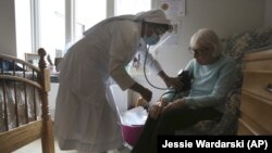 Sister Rose Nellivila checks the blood pressure of Lorraine Catney, a resident of Villa Angela at St. Anne Home nursing facility in Greensburg, Pa., Thursday, March 25, 2021. (AP Photo/Jessie Wardarski)