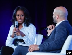 Former first lady Michelle Obama talks with Sam Kass, former White House Chef and Senior Policy Adviser for Nutrition, at the Partnership for a Healthier American 2017 Healthier Future Summit in Washington, May 12, 2017