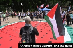 Seorang pengunjuk rasa mengibarkan bendera selama unjuk rasa untuk mendukung warga Palestina di Sydney, Australia, 6 Oktober 2024. (Foto: AAP/Mick Tsikas via REUTERS)