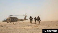 FILE - Afghan National Army 215th Corps troops disembark an Afghan Air Force Black Hawk helicopter during a troop resupply at Camp Shorabak in Helmand province, July 28, 2018. 