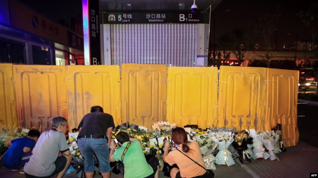 河南郑州市民在被黄色围栏围起来的地铁5号线车站前献花悼念水灾死难者。（2021年7月26日）(photo:VOA)