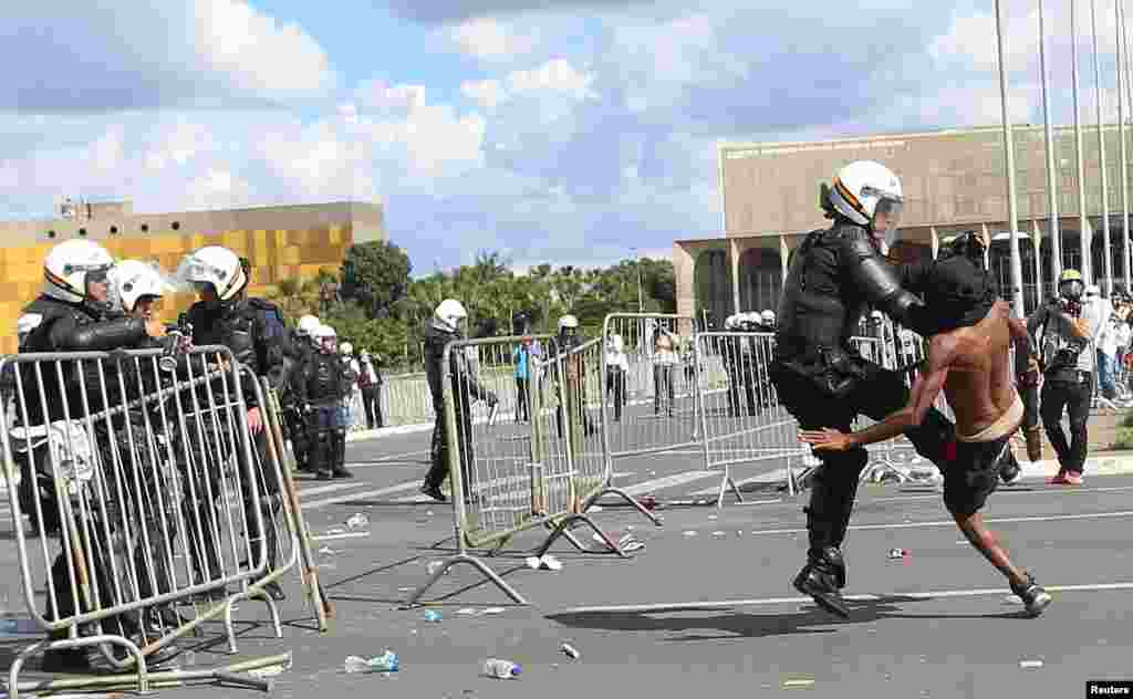 A demonstrator clashes with a riot police officer during a protest against President Michel Temer and the latest corruption scandal, in Brasilia, Brazil.