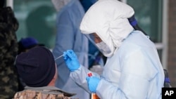 28일 미국 유타주 솔트레이크 카운티 보건국 관계자들이 청사 앞에서 주민들에게 신종 코로나바이러스 감염 검사를 진행하고 있다. 