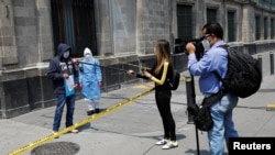 Periodistas entrevistan a un hombre que dice estar contagiado con coronavirus, mientras protesta en las afueras del Palacio Nacional de Ciudad de México. 28 de mayo de 2020.