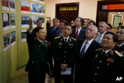 Vietnam's Defense Minister Ngo Xuan Lich, left, and U.S. Secretary of Defense Jim Mattis, second from right, attend a photo exhibition on Vietnam-US military cooperation after their meeting in Hanoi, Vietnam. Jan. 25, 2018. (Kham/Pool Photo via AP)