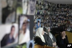 FILE - Bosnian women watch a TV broadcast of Bosnian Serb leader Milorad Dodik, testifying in Radovan Karadzic's defense at The Hague, in Tuzla, Bosnia, April 9, 2013.