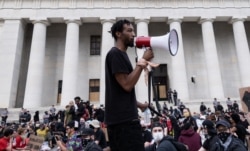 Protesters listen to a man speak as they gather peacefully in front of the Ohio Statehouse in Downtown Columbus, Ohio, June 1, 2020, to protest the death of George Floyd.