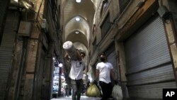 Men carry their goods through mostly closed Tehran's Grand Bazaar, Iran, March 17, 2020. The new coronavirus ravaging Iran is cutting into celebrations marking the Persian New Year, known as Nowruz.