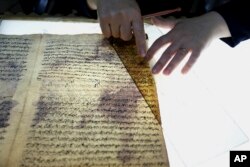 Seorang anggota staf restorasi perpustakaan memeriksa sebuah dokumen yang rusak di Perpustakaan Nasional Baghdad di Irak, 28 Juli 2015. (AP/Karim Kadim)