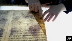 A member of the library restoration staff works on a damaged document at the Baghdad National Library in Iraq, July 28, 2015.