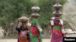 Villagers hold pitchers of drinking water on their head as they walk to get water for their families at the village of Bhattian Jivery in Tharparkar, Pakistan. (FILE)