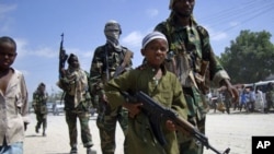 A young boy leads the hard-line Islamist Al Shabab fighters as they conduct military exercise in northern Mogadishu's Suqaholaha neighborhood, Somalia. (File)