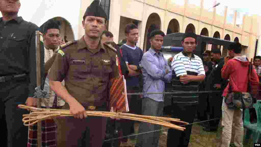 A policeman displays canes used to whip convicted criminals under Aceh's Shariah law, Dec. 5, 2014. (Maimun Saleh/VOA﻿)