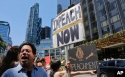 FILE - Protesters rally outside a Trump hotel to call for the impeachment of President Donald Trump, July 2, 2017, in New York.