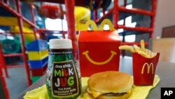 Una Happy Meal de leche con chocolate sin grasa y una hamburguesa con papas fritas, se preparan para una foto en un restaurante de McDonald's en Brandon, Mississippi, el miércoles 14 de febrero de 2018. McDonald's pronto eliminará las hamburguesas con queso y la leche con chocolate del menú de la Cajita Feliz. (AP Photo / Rogelio V. Solis)