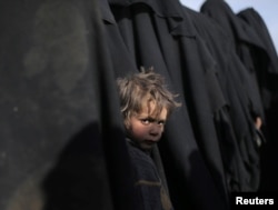 A boy looks at the camera near Baghuz, Deir el-Zour province, Syria, March 5, 2019.