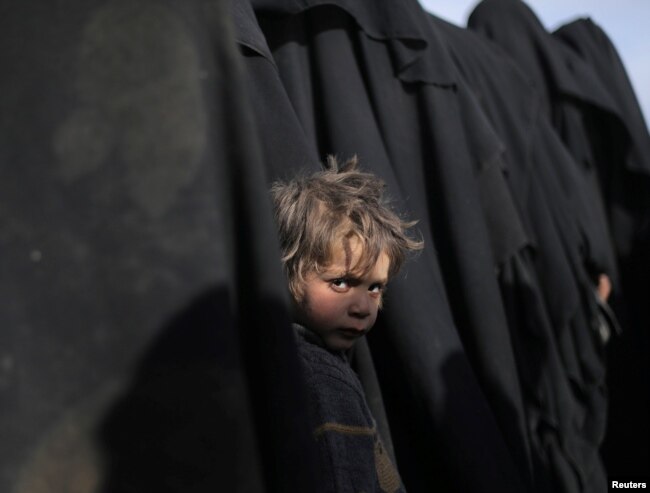 A boy looks at the camera near Baghuz, Deir el-Zour province, Syria, March 5, 2019.