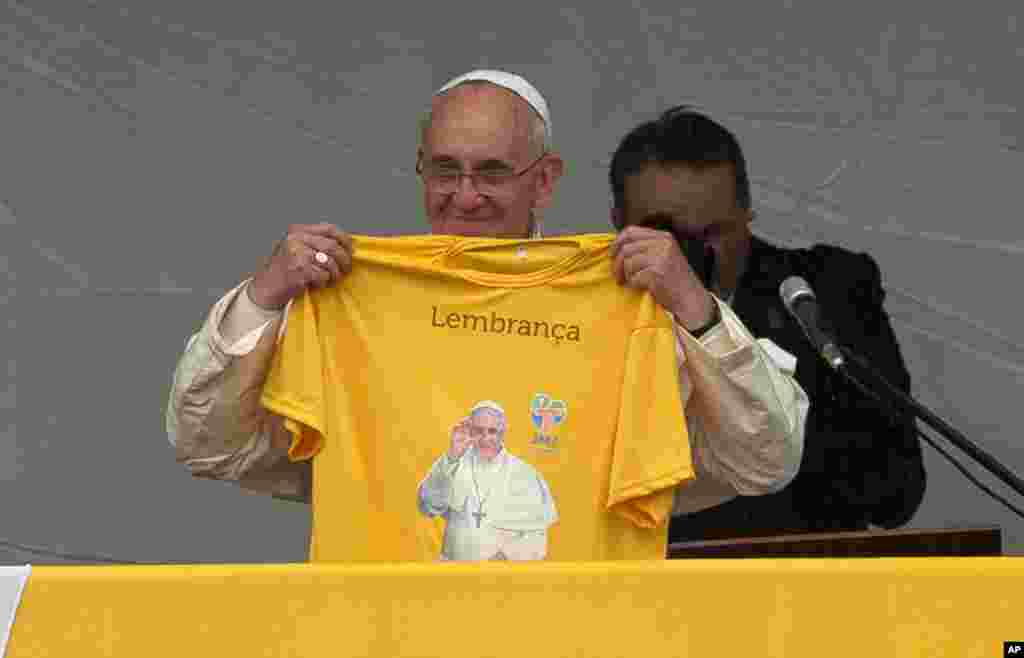 Pope Francis holds a T-shirt with his photo and the Portuguese word &quot;Memory&quot; toward the crowd in the Varginha area of the Manguinhos slum complex in Rio de Janeiro, July 25, 2013.