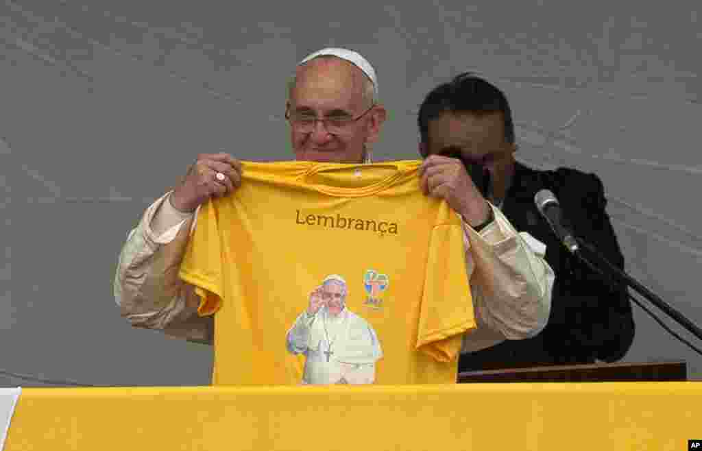 Pope Francis holds a T-shirt with his photo and the Portuguese word "Memory" toward the crowd in the Varginha area of the Manguinhos slum complex in Rio de Janeiro, July 25, 2013.