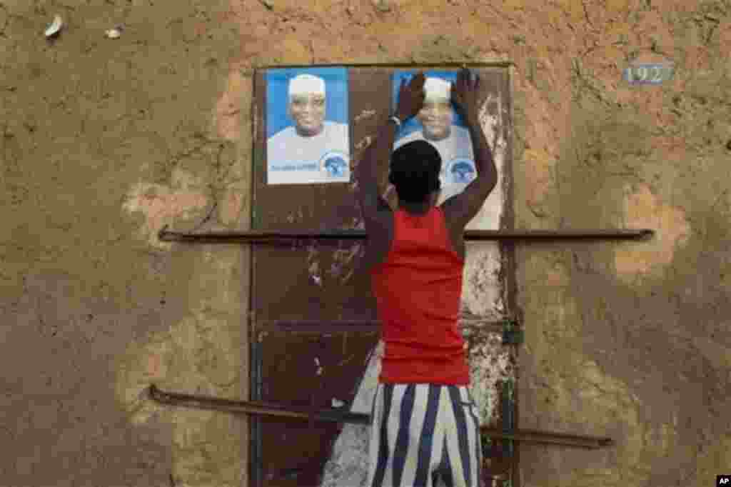 Young man glues campaign posters for Ibrahim Boubacar Keita on top of a pair posters for rival Dramane Dembele, Gao, Mali, July 25, 2013.