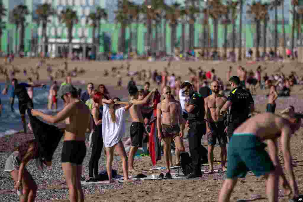 Police officers ask people to refrain from sitting on the beach in Barcelona, Spain, as sunbathing and recreational swimming are still not allowed.