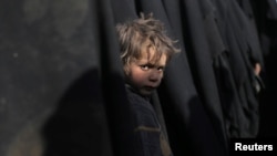 A boy looks at the camera near Baghuz, Deir Al Zor province, Syria, March 5, 2019. 