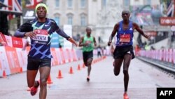 Shura Kitata, à gauche, traverse la ligne d'arrivée devant Vincent Kipchumba et Sisay Lemma au marathon de Londres, Angleterre, le 4 octobre 2020.