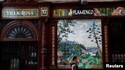 FILE - A man wearing a protective mask walks past a closed flamenco bar, amid the coronavirus disease outbreak, in Madrid, Spain, June 30, 2020. 
