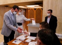 FILE - In this photo released on the official Facebook page of Syrian Presidency, Syrian President Bashar Assad and his wife Asma vote at a polling station in the parliamentary elections in Damascus, Syria, July 19, 2020.