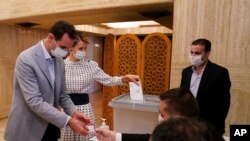In this photo released on the official Facebook page of Syrian Presidency, Syrian President Bashar Assad and his wife Asma vote at a polling station in the parliamentary elections in Damascus, Syria, July 19, 2020. 