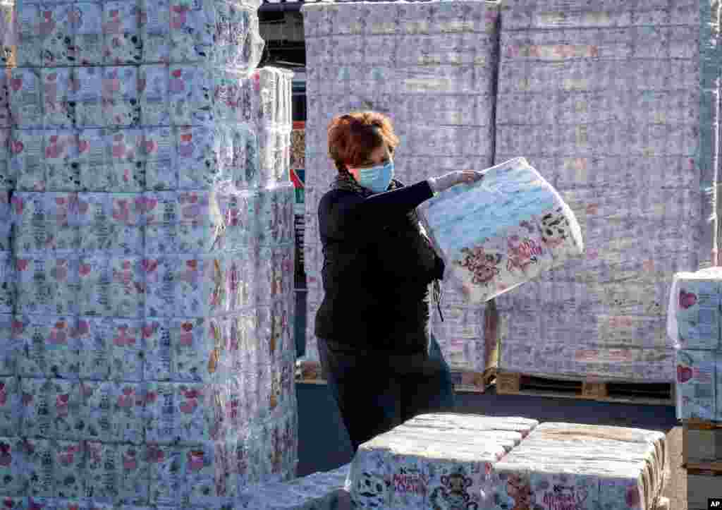 A woman stacks up toilet paper rolls at a "toilet paper drive-in" that has been set up in a parking lot in Dornburg, Germany.